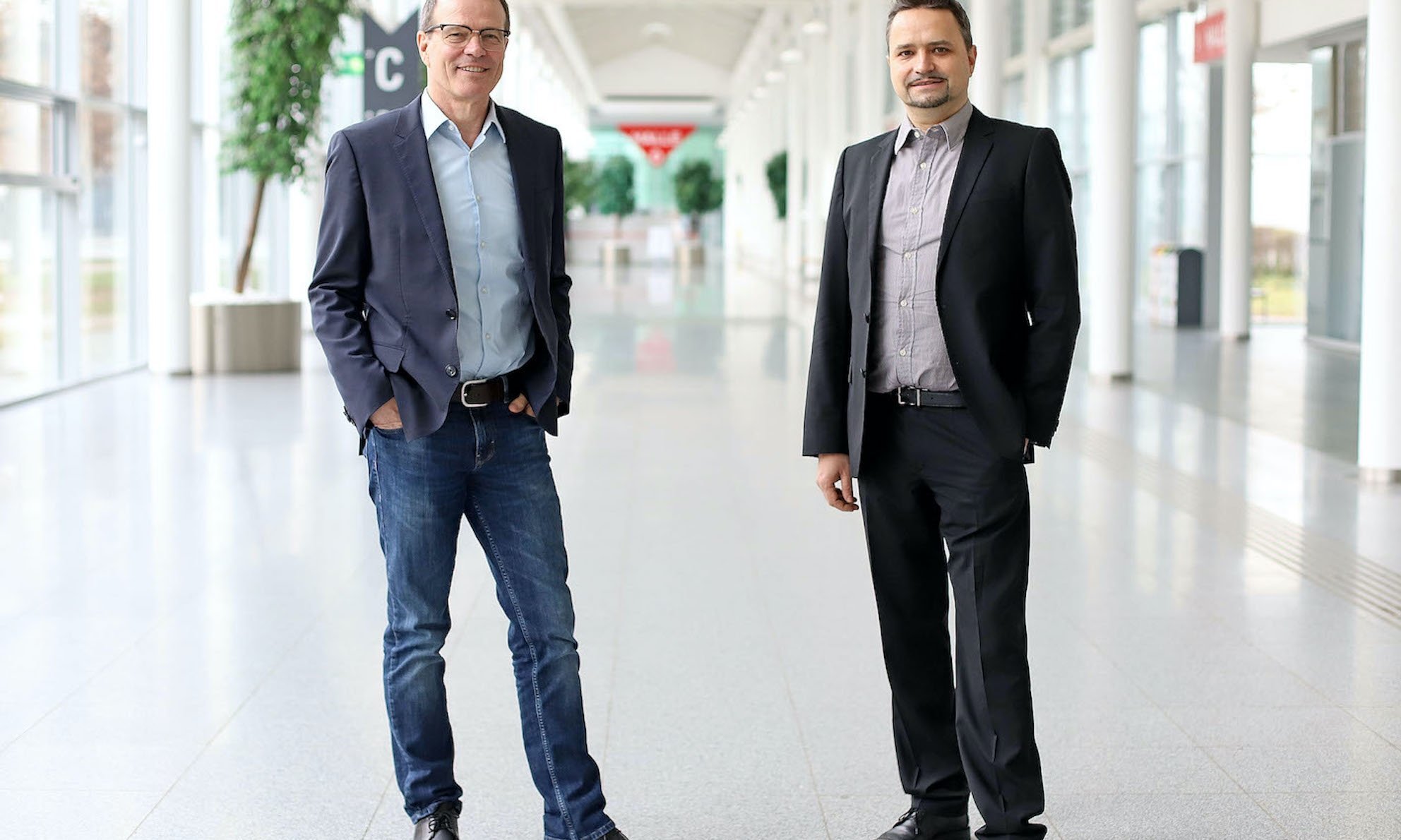 Zwei Herren stehen im Anzug in einem lichtdurchfluteten langen Gang in der Mall der Messe Wien