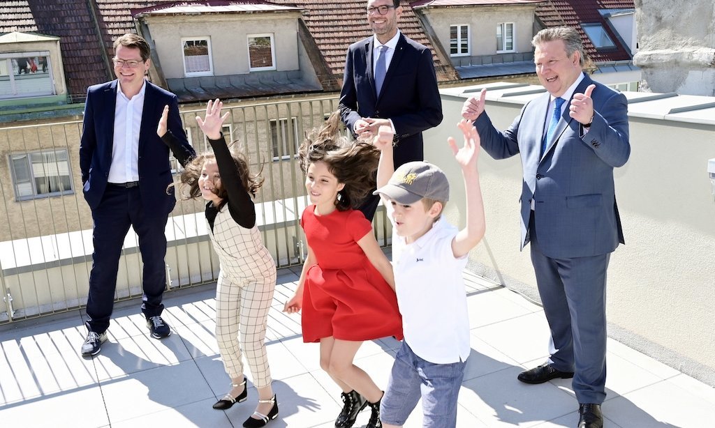 Drei Erwachsene und drei Kinder stehen auf einer Freifläche der neuen Schule